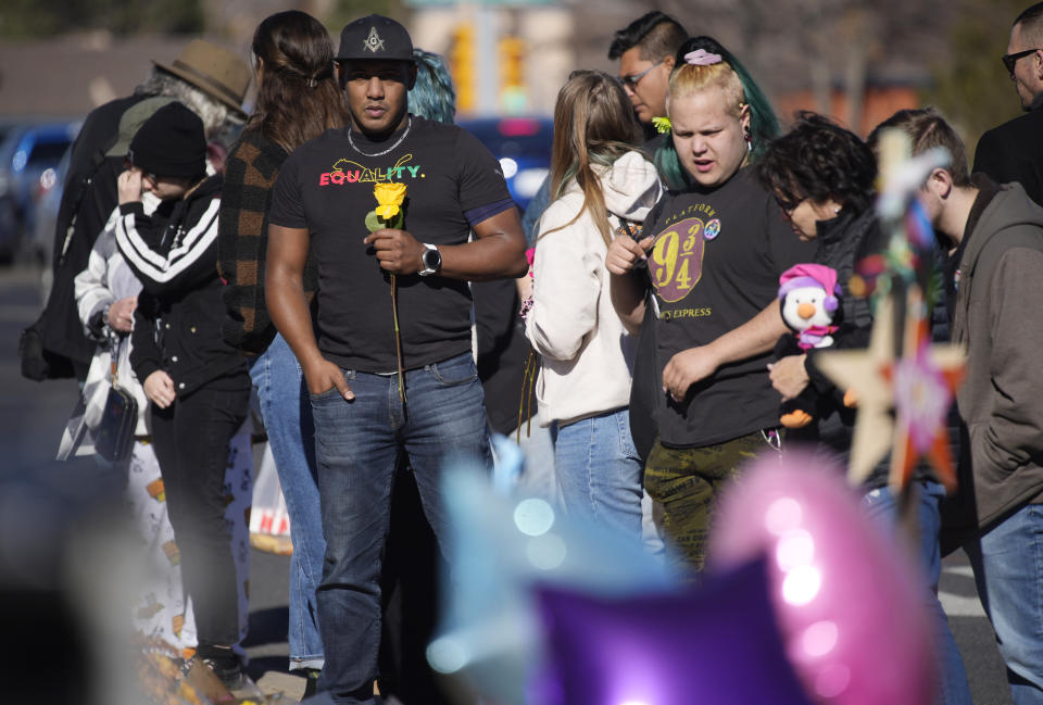 Joseph Alvarez, left, holds a rose while joining other people at a makeshift display of bouquets of flowers on a corner near the site of a mass shooting at a gay bar Monday, Nov. 21, 2022, in Colorado Springs, Colo. (AP Photo/David Zalubowski)