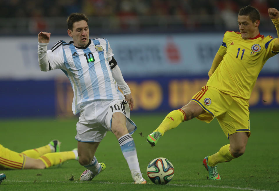 A laser spot shines on Argentina's Lionel Messi, left, as he challenges for the ball with Romania's Gabriel Torje, right, during an international friendly soccer game on the National Arena stadium in Bucharest, Romania, Wednesday, March 5, 2014.. (AP Photo/Vadim Ghirda)