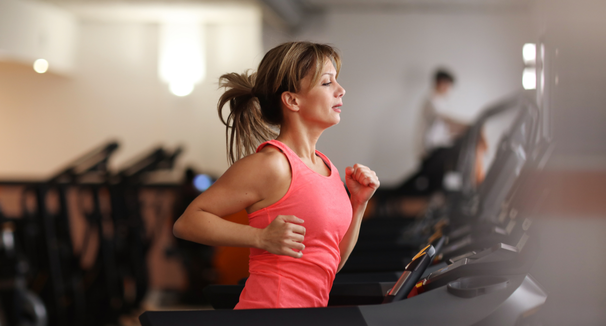 woman in pink top running on treadmill in gym, treadmills