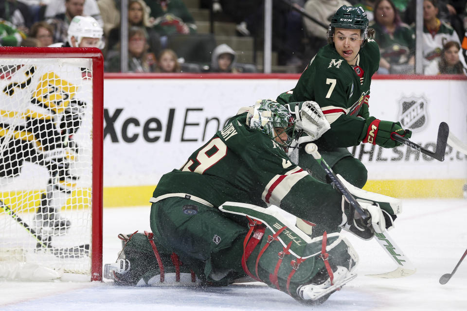 Minnesota Wild goaltender Marc-Andre Fleury (29) deflects a shot while defenseman Brock Faber (7) watches during the second period of an NHL hockey game against the Pittsburgh Penguins Friday, Feb. 9, 2024, in St. Paul, Minn. (AP Photo/Matt Krohn)