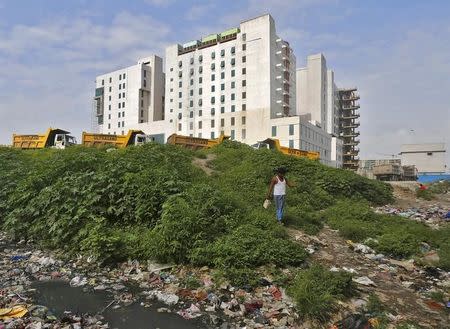 A man walks on the garbage near the Gleneagles Khubchandani hospital in Mumbai, India, August 26, 2015. REUTERS/Shailesh Andrade