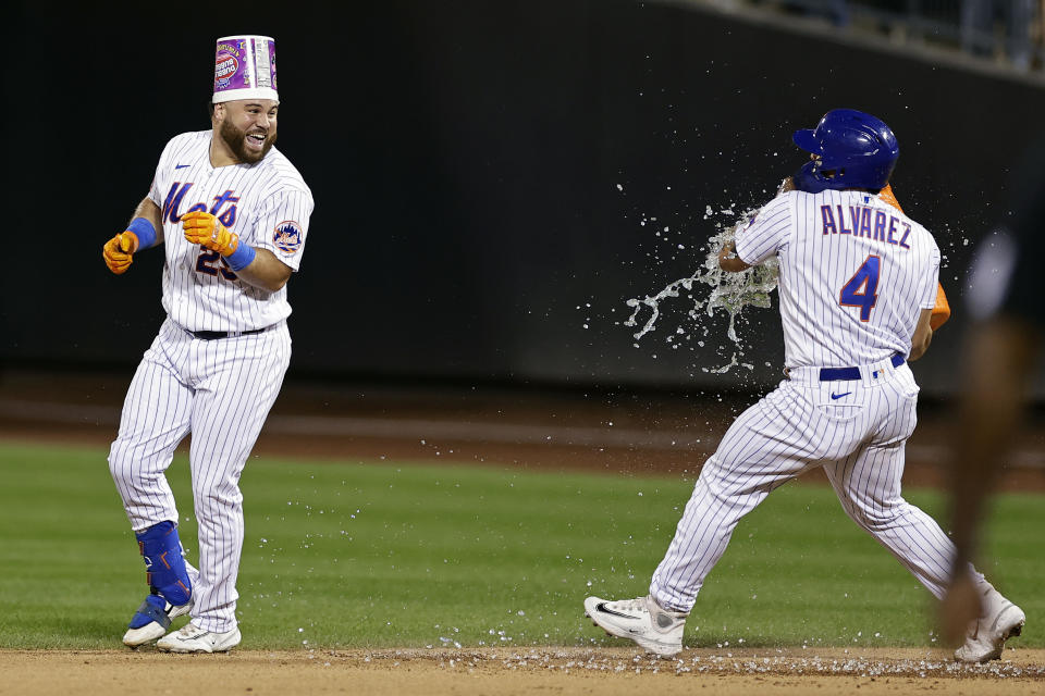 New York Mets' Francisco Alvarez, right, prepares to douse DJ Stewart after Stewart was hit by a pitch with the bases loaded to drive in the winning run against the Texas Rangers during the 10th inning of a baseball game Wednesday, Aug. 30, 2023, in New York. The Mets won 6-5. (AP Photo/Adam Hunger)