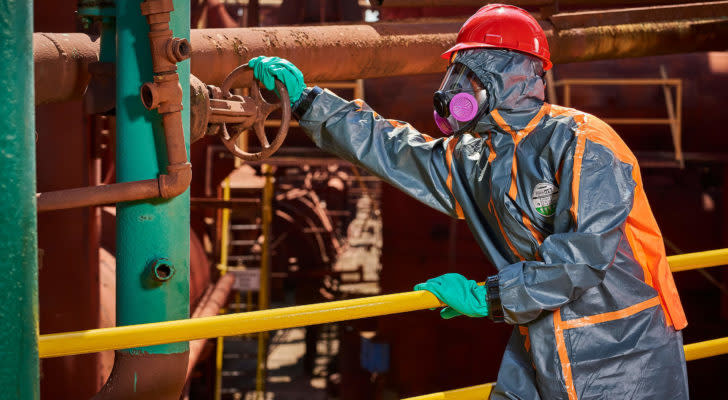 An image of a person in a Hazmat suit turning a handle