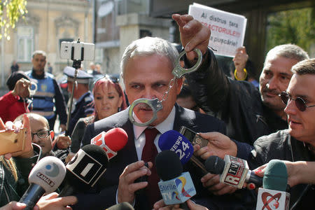 FILE PHOTO: A protester waves a pair of handcuffs in front of Social Democrat Party leader Liviu Dragnea in Bucharest, Romania, October 3, 2017. Inquam Photos/Octav Ganea via REUTERS/File Photo