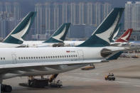 FILE - In this Aug. 12, 2019, file photo, ground crew drive past Cathay Pacific and Cathay Dragon Airways planes park at the Hong Kong International Airport. Hong Kong airline Cathay Pacific Airways on Wednesday, Oct. 21, 2020, said it would cut 8,500 jobs and shut down its regional airline unit in a corporate restructuring, as it grapples with the plunge in air travel due to the pandemic. (AP Photo/Vincent Thian, File)