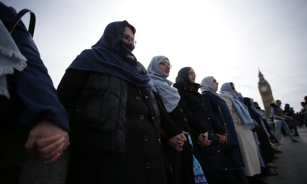 Women activists wearing blue hold hands on Westminster Bridge.