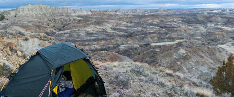 Campsite with a tent and hunting gear in the badlands area of the border of Eastern Montana and Western North Dakota on an early winter day. Overcast sky. Concept for public / BLM land use