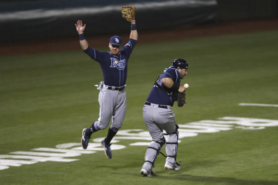 Tampa Bay Rays' Mike Zunino, right, misses a foul ball hit by Oakland Athletics' Tony Kemp as Mike Brosseau avoids the play during the seventh inning of a baseball game in Oakland, Calif., Friday, May 7, 2021. (AP Photo/Jed Jacobsohn)