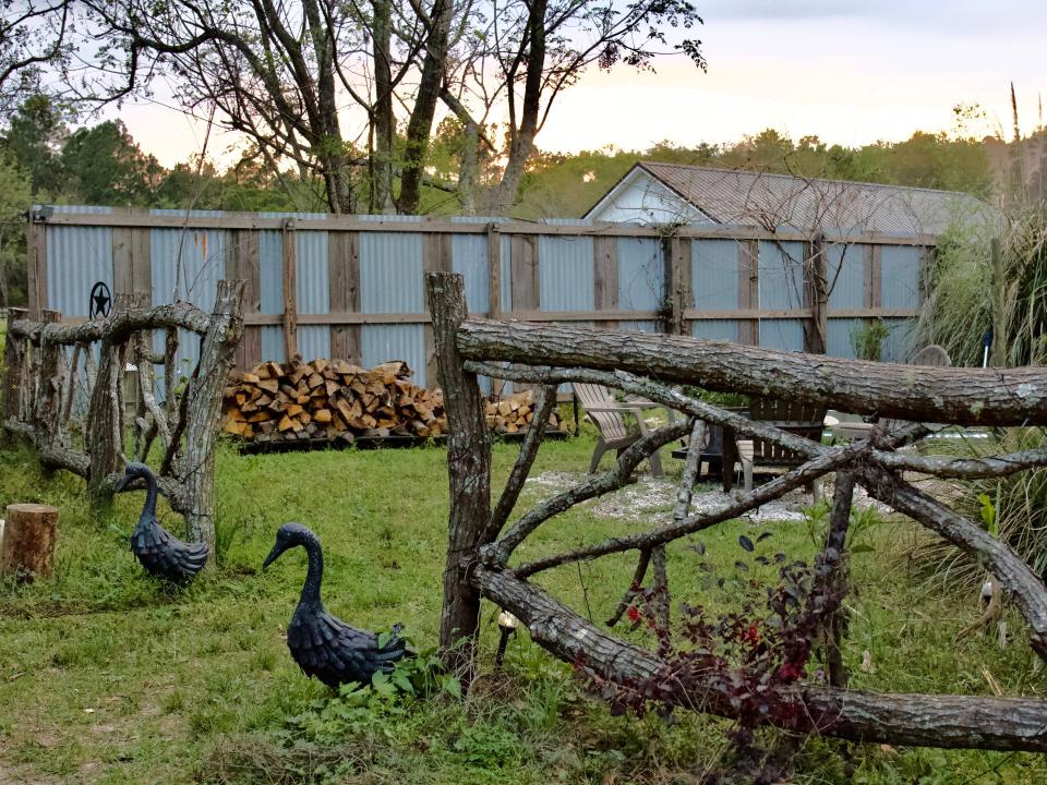 View of a green backyard with a wooden fence and two statues of geese