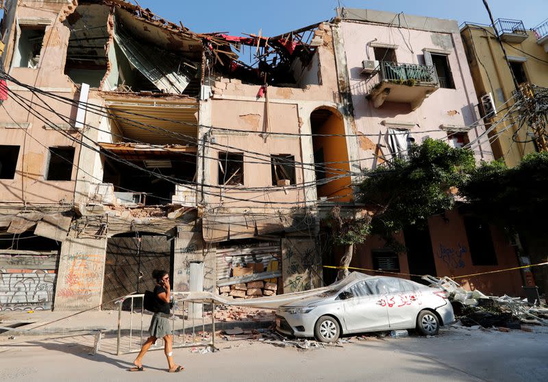 A woman walks past a damaged area in the aftermath of a massive explosion in Beirut