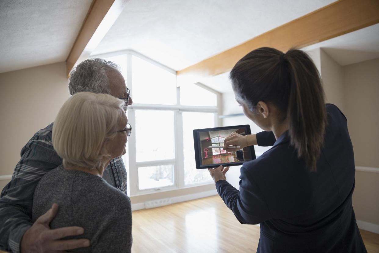 interior designer with digital tablet showing senior couple augmented reality, planning living room remodel