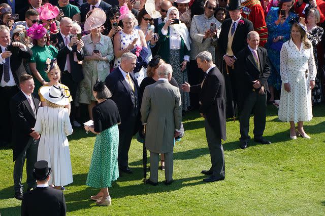 <p>STEFAN ROUSSEAU/POOL/AFP via Getty Images</p> King Charles (center) and Queen Camilla (left) greet guests at the Buckingham Palace garden party on May 8, 2024.