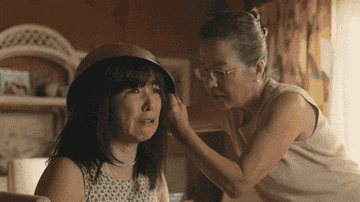 GIF of a woman cutting her daughter's hair in "PEN15"