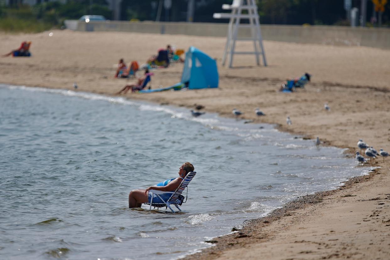 A woman takes shelter from the sweltering heat by sitting on her chain in the water on East Beach in New Bedford.
