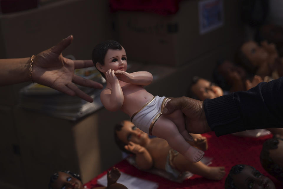 Locals handle Baby Jesus figures for sale in Mexico City, Wednesday, Jan. 25, 2023. As Mexicans prepare to celebrate "Dia de la Candelaria" or Candlemas people buy Baby Jesus figures as part of the celebration. (AP Photo/Marco Ugarte)