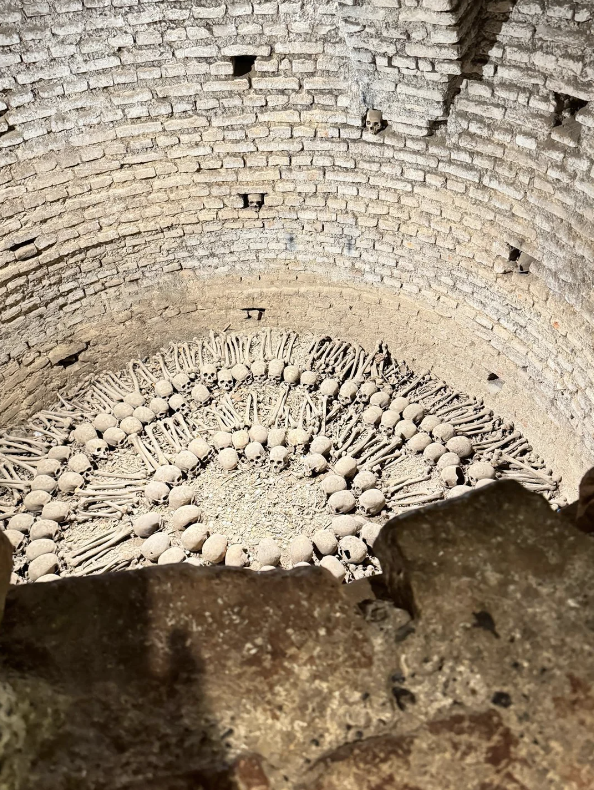 Ancient well filled with skeletal remains and artifacts, viewed from above