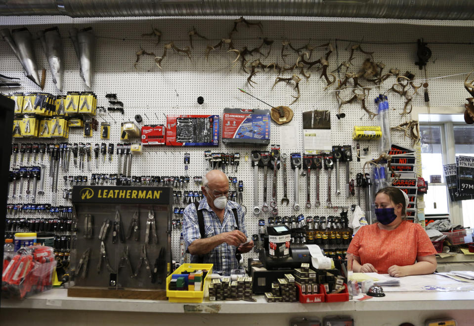 In this Monday, May 4, 2020, photo, Aaron Hurst, 67, left, wears a mask as he runs his AAA Farm Supply business in Terre Hill, Pa. (AP Photo/Jessie Wardarski)