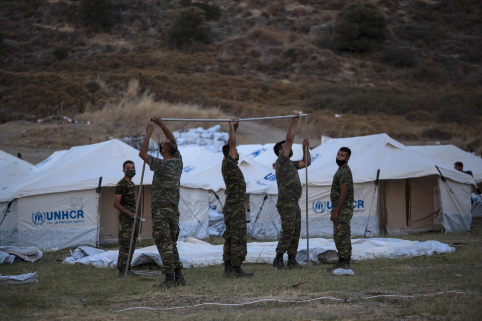 Greek soldiers set up UNHCR tents at a shooting range to accommodate refugees, in Lesbos Island, Greece, Friday, Sept. 11, 2020. Some thousands of refugees and migrants have spent a third night in the open on the Greek island of Lesbos after two consecutive nights of fires in the notoriously overcrowded Moria camp left them homeless. (AP Photo/Petros Giannakouris)