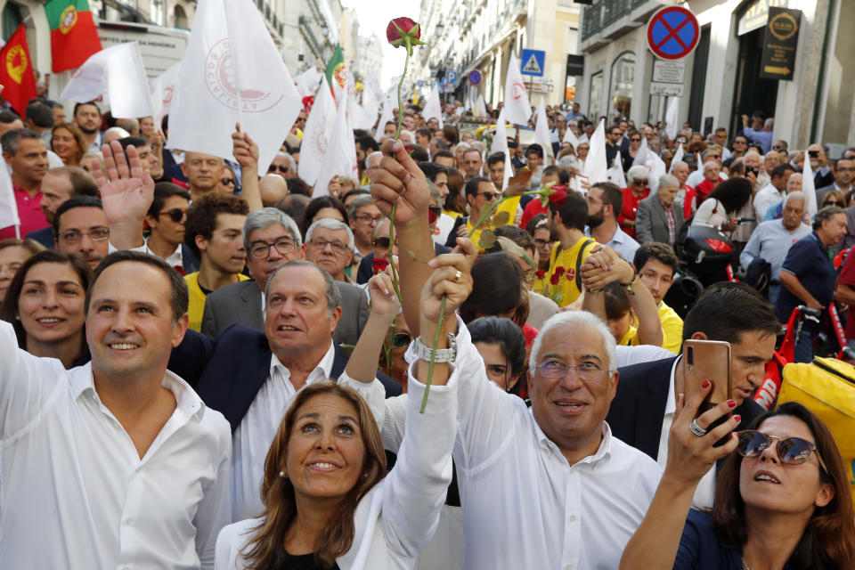 Portuguese Prime Minister and Socialist Party leader Antonio Costa, center right, with his wife Fernanda Tadeu, center, and Lisbon Mayor Fernando Medina, left, wave to supporters during an election campaign action in downtown Lisbon Friday, Oct. 4, 2019. Portugal will hold a general election on Oct. 6 in which voters will choose members of the next Portuguese parliament. The ruling Socialist Party hopes an economic recovery during its four years of governing will persuade voters to return the party to power. (AP Photo/Armando Franca)