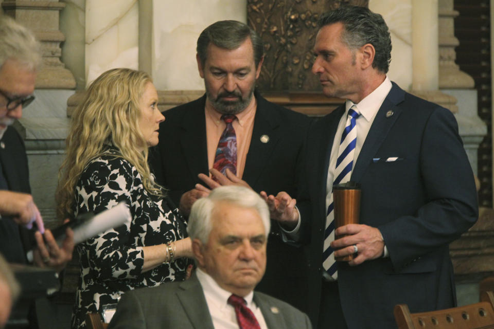 Kansas Senate President Ty Masterson, right, R-Andover, confers with Sen. Virgil Peck, R-Havana, a Senate negotiator on tax issues, and Michelle Schroeder, Masterson's top aide, during a Senate session, Friday, April 5, 2024, at the Statehouse in Topeka, Kan. Lawmakers have approved a plan backed by Masterson and other Republicans to cut taxes by more than $1.5 billion over three years. (AP Photo/John Hanna)