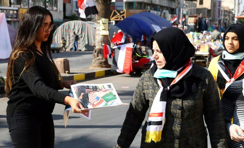 An Iraqi demonstrator distributes Tuktuk newspaper during the ongoing anti-government protests, in Baghdad