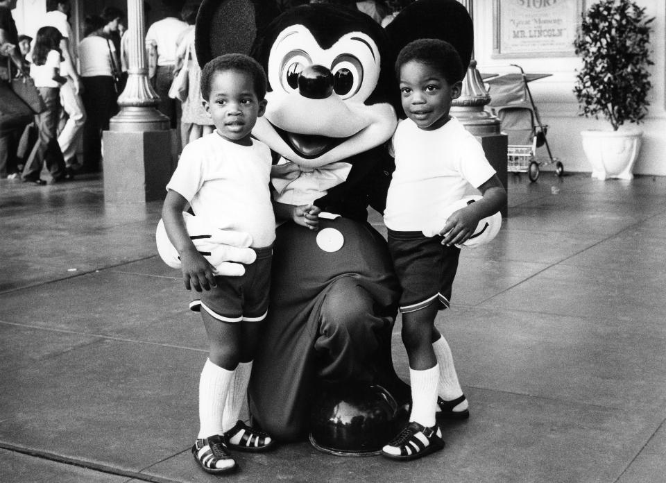 Two children pose with Mickey Mouse at Disneyland in 1982.