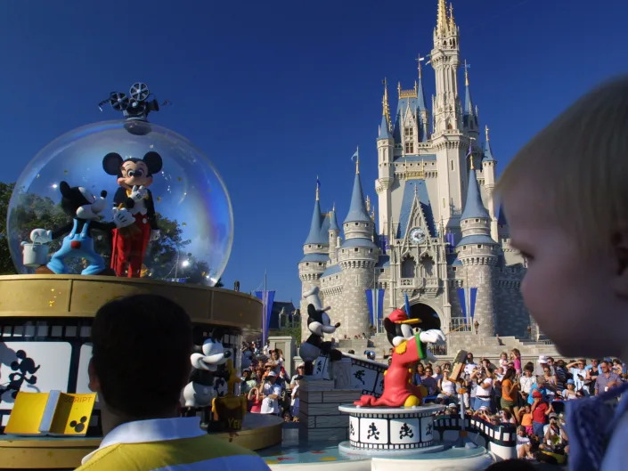 Mickey Mouse in a giant snow globe parade float in front of Cinderella's Castle.