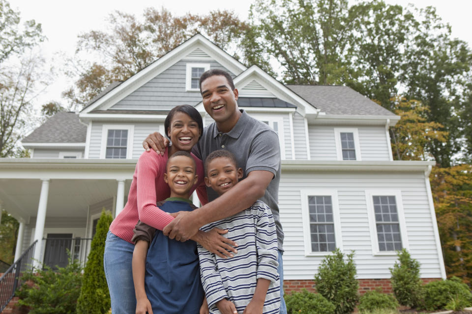 Black family standing together in front of house