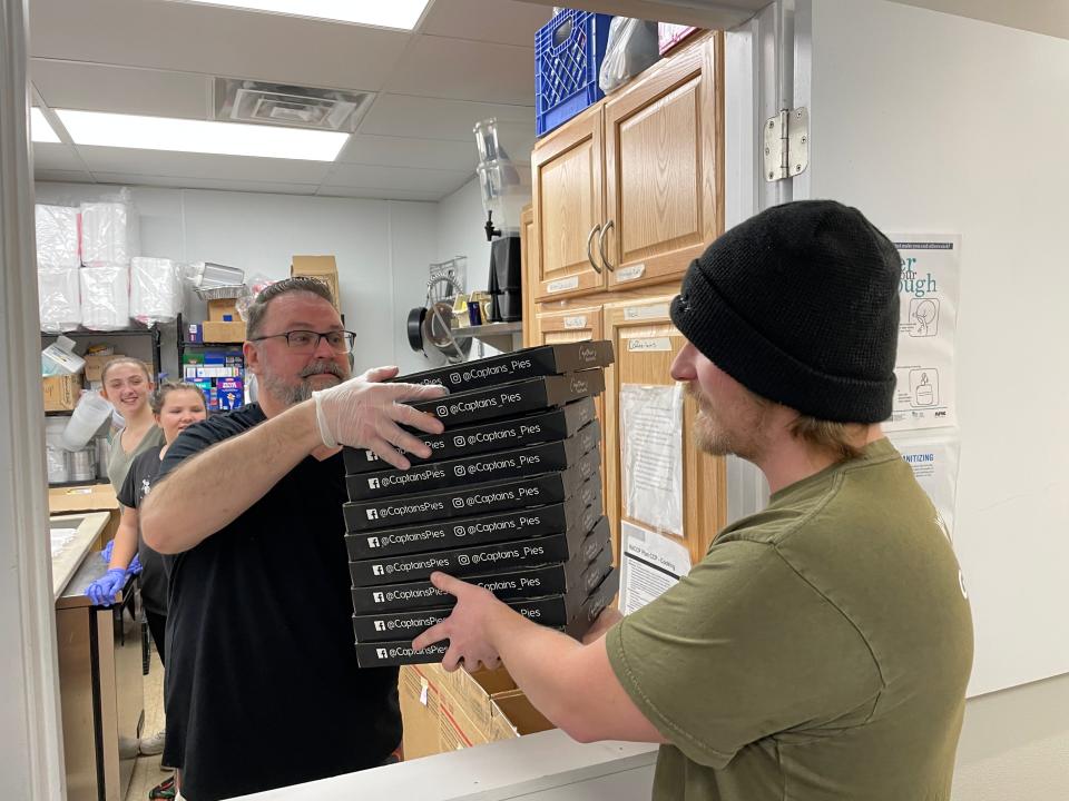 Captain's ön Main owner Nick Mannisto hands a stack of pizzas to Bountiful Harvest's Brian Sadowski.