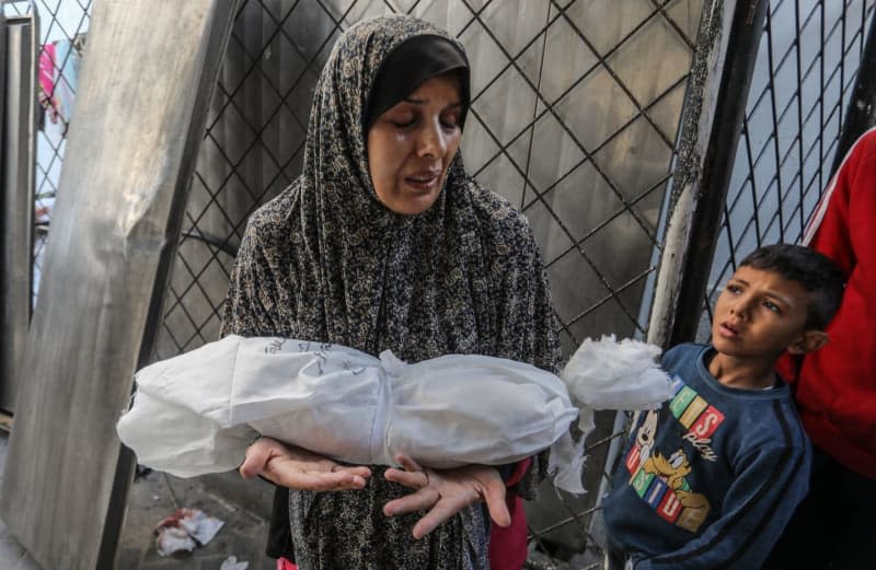 A Palestinian woman carries the wrapped body of a her infant, killed in Israeli bombardment, after battles resumed between Israel and the Hamas movement. Abed Rahim Khatib/dpa