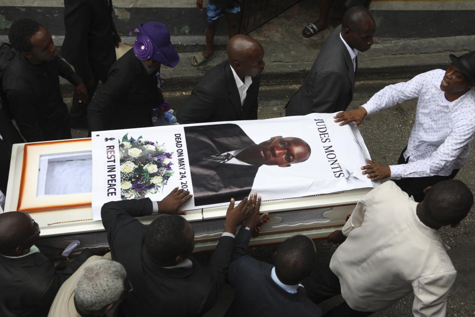 People transport the coffin of mission director Judes Montis, killed by gangs alongside two of his U.S. missionary members, to the cemetery after his funeral ceremony in Port-au-Prince, Haiti, Tuesday, May 28, 2024. The service also honored the lives of Davy and Natalie Lloyd, featured on the photo on the back of the hearse, a married couple in their early 20s who was with Montis when gunmen ambushed them on Thursday night, May 23, as they left a youth group activity held at a local church. (AP Photo/Odelyn Joseph)