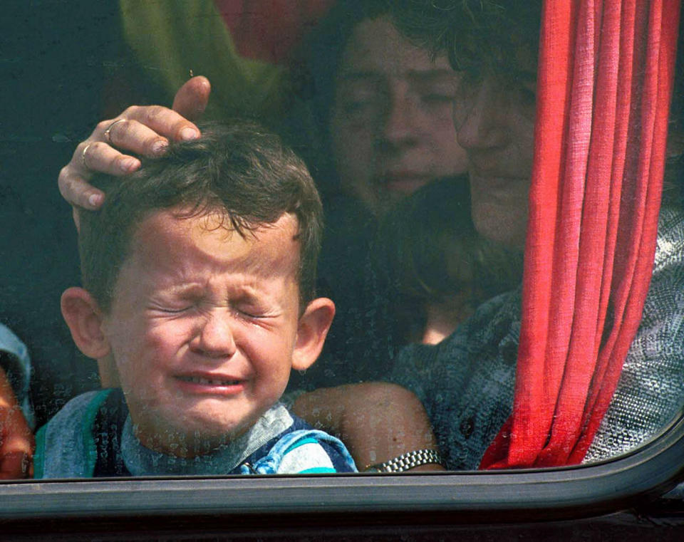 <p>A Serbian boy is comforted as he cries and presses his head against the window of a bus while fleeing the town of Kosovo Polje, outside Pristina, for the town of Nis in Serbia, Sept. 17, 1999. (Photo: Jacqueline Larma/AP) </p>