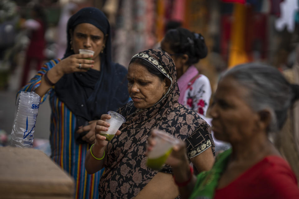 Shoppers drink juice in plastic glasses as they take a break at a weekly market in New Delhi, India, Wednesday, June 29, 2022. India banned some single-use or disposable plastic products Friday as a part of a longer federal plan to phase out the ubiquitous material in the nation of nearly 1.4 billion people. (AP Photo/Altaf Qadri)