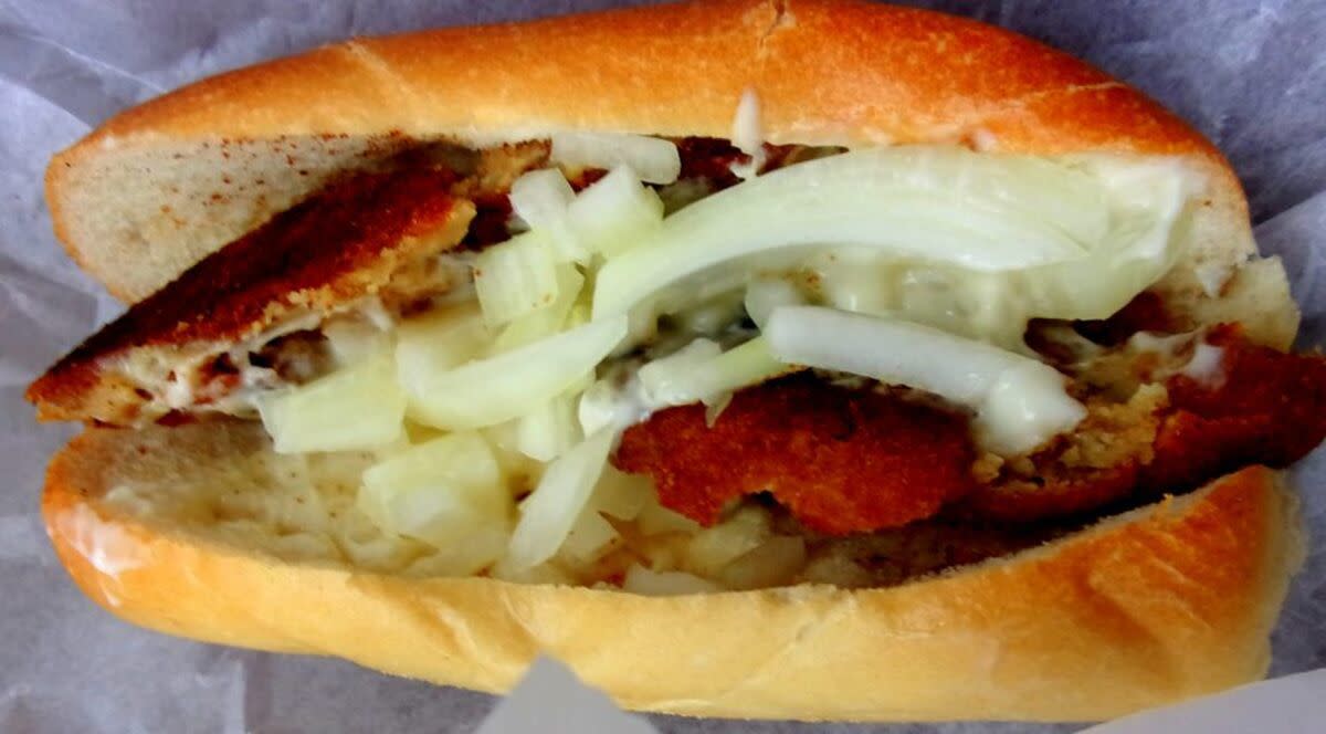 Closeup of a Philly Fish Cake Sandwich with onions and horseradish sauce on white serving paper, Johnny Hots, Philadelphia