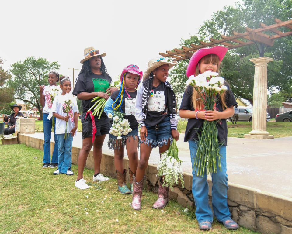 Young girls stand with flowers Wednesday at the marker ceremony for Bones Hooks at Bones Hooks Park in Amarillo.