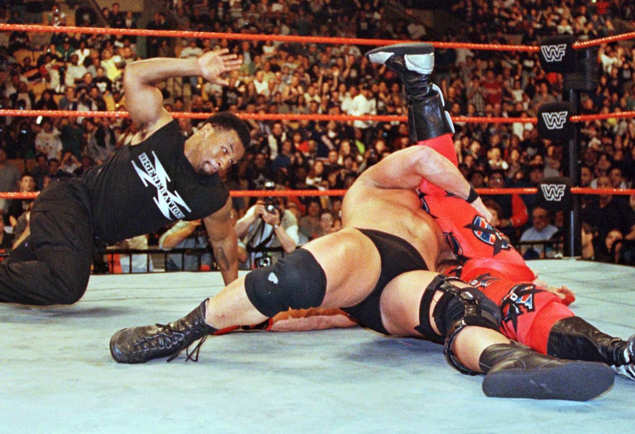 Former heavyweight boxing champion Mike Tyson (L) slaps the mat three times to signal a pin and end the World Wrestling Federation championship match as his supposed ally Shawn Michaels of 