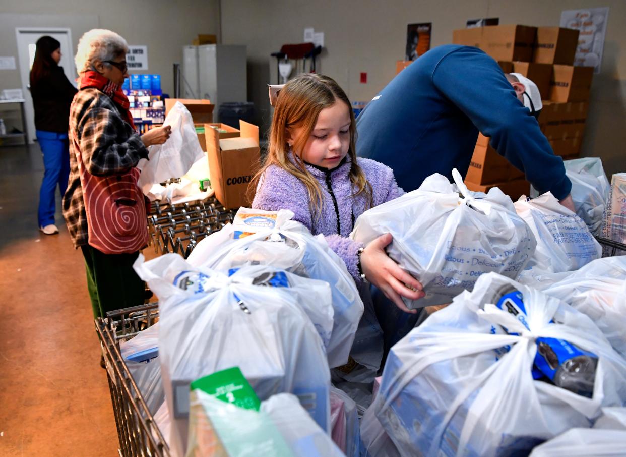 Kate Remsnyder, 8, stacks a bundle of items in a basked beside her father Joel while volunteering at the Food Bank of West Central Texas on Feb. 17.