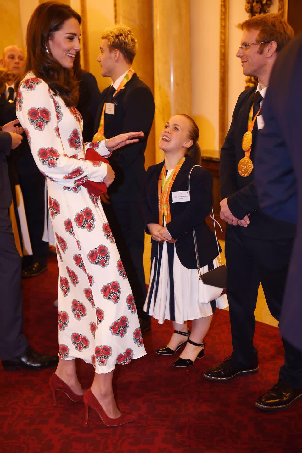 <p>The Duchess wears a rose-patterned Alexander McQueen dress with red suede pumps and a red clutch while meeting Olympic and Paralympic athletes at Buckingham Palace.</p>