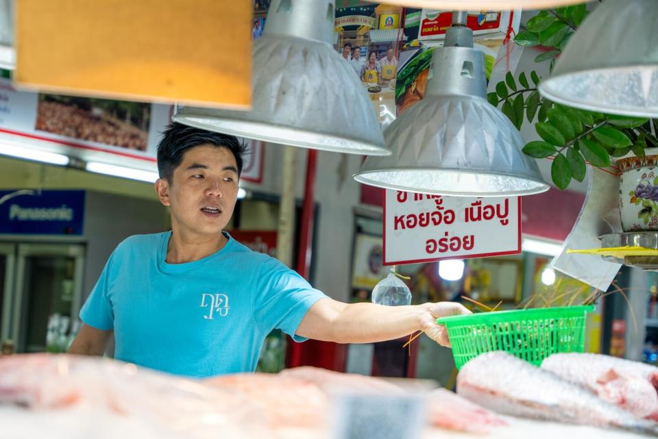 Chef Ton shopping at a local market, where he buys a basket of shrimp from one of the vendors.