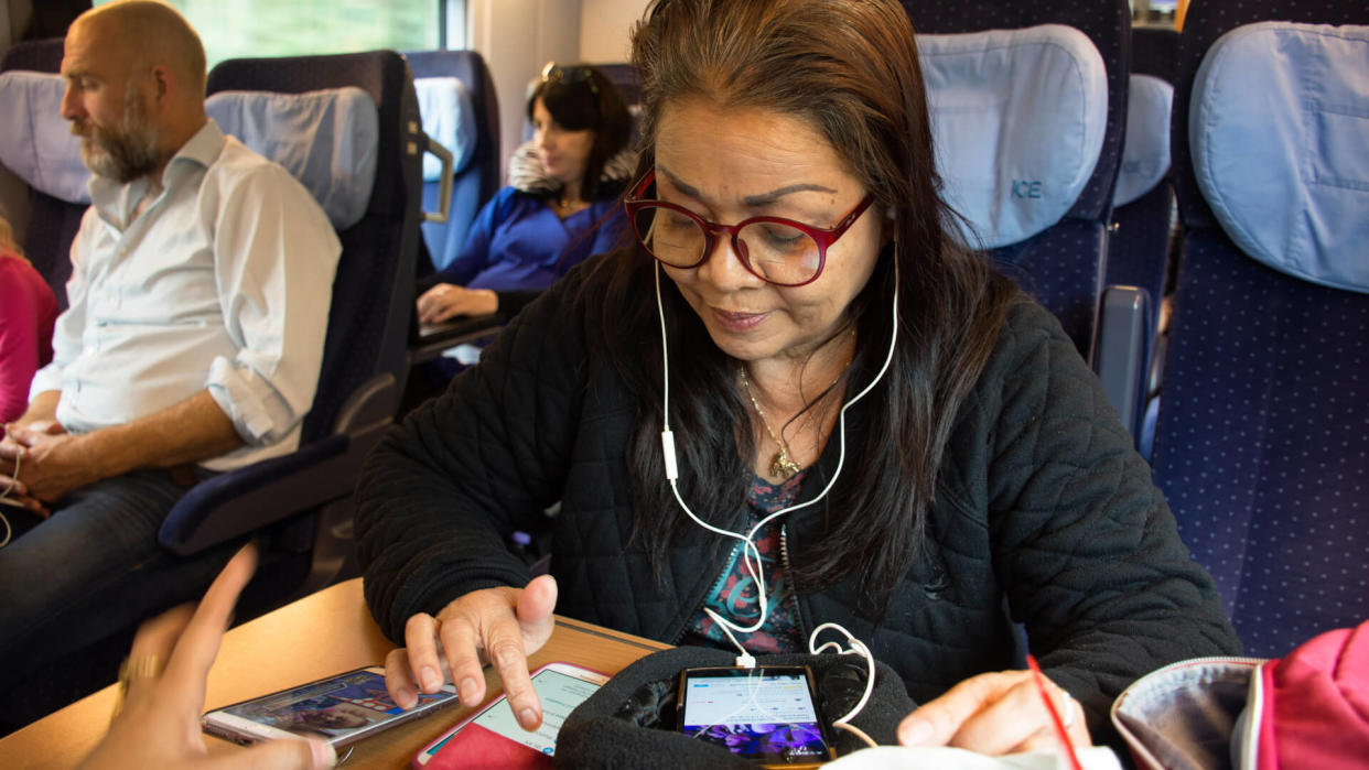 Old woman playing moblie phone and listen music while sit on train running from France go to Germany on September 7, 2017 in Nuremberg, Germany.