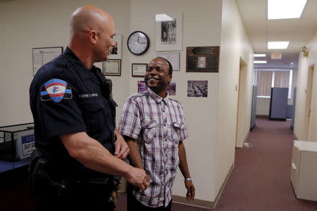 Lewiston Police Officer Patrick Griffin (L), a community resource officer, talks to Jama Mohamed, literacy and volunteering director at Maine Immigrant and Refugee Services facility, in Lewiston, Maine June 1, 2015. REUTERS/Brian Snyder