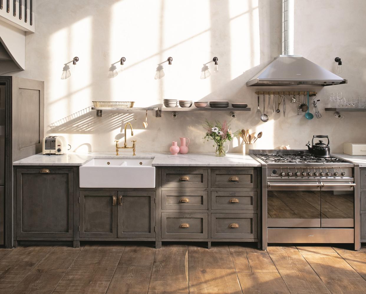  A kitchen with a butler sink, grey cabinetry, and stainless steel appliances. 