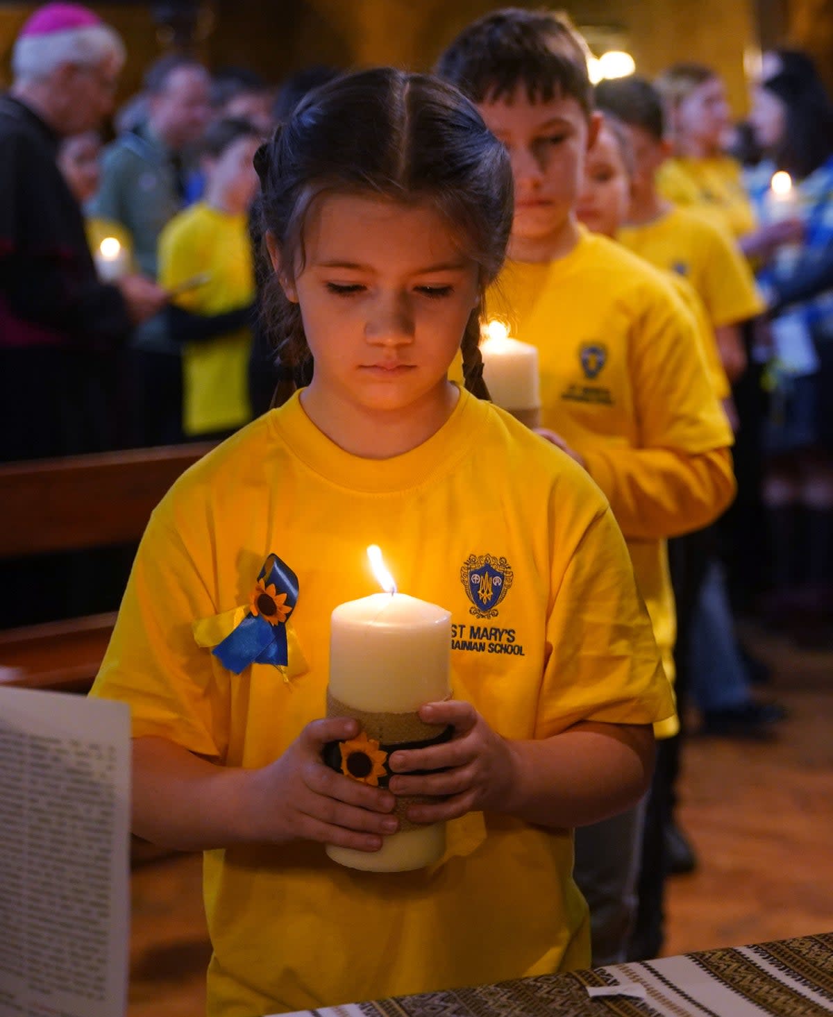 Children from St Mary’s Ukrainian School lighting 52 candles - one for each week of the war (PA)
