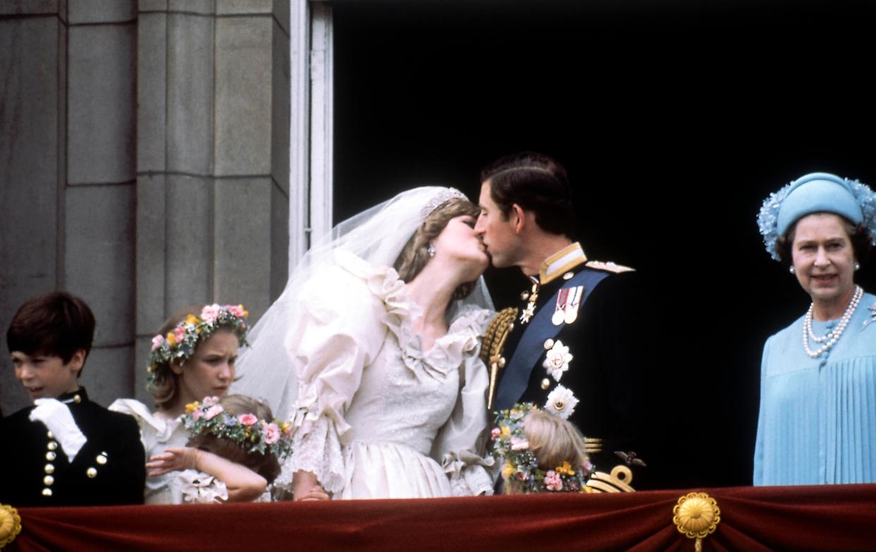 Britain's Prince Charles kisses his bride, Lady Diana Spencer, the new Princess of Wales, on the Balcony of Buckingham Palace in London, England on July 29, 1981 after their wedding at St. Paul's Cathedral. Queen Elizabeth II stands at right. 