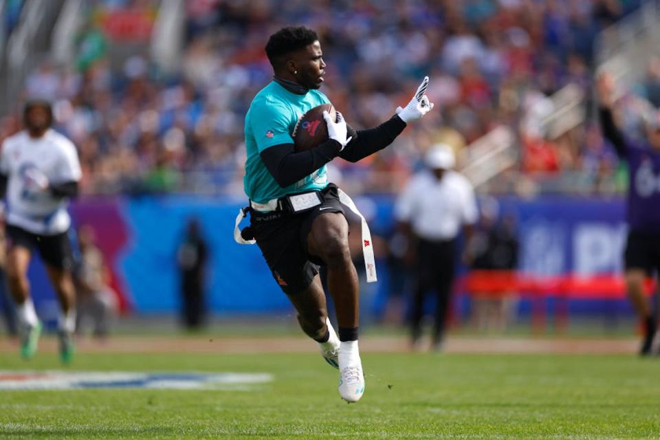 Young man runs holding a football and waving his finger mid-stride.