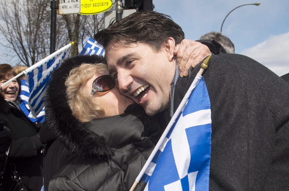 Prime Minister Justin Trudeau is hugged by a member of the crowd as he attends the Greek Independence Day parade in Montreal, Sunday, April 3, 2016. THE CANADIAN PRESS/Graham Hughes