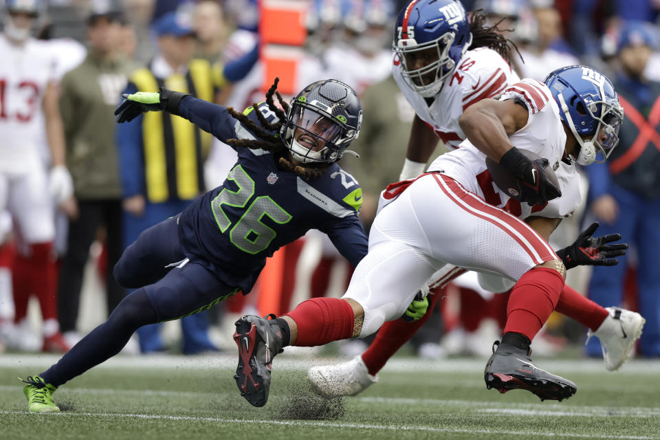 New York Giants running back Saquon Barkley, right, runs against Seattle Seahawks safety Ryan Neal during the first half of an NFL football game in Seattle, Sunday, Oct. 30, 2022. (AP Photo/John Froschauer)