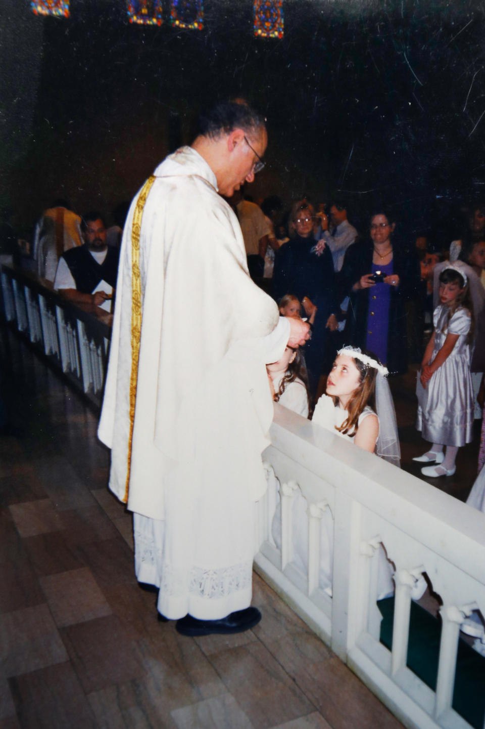 This undated photo provided by Mary Rose Maher shows her as a child during her First Dommunion with Father Eduard Perrone at The Assumption of the Blessed Virgin Mary Church in Detroit. For 25 years, the Rev. Eduard Perrone presided over the church, also known as Assumption Grotto. In July 2019, his parishioners were shocked when Perrone, 70, was removed from ministry after a church review board decided there was a “semblance of truth” to allegations that he abused a child decades ago. He told The Associated Press he “never would have done such a thing.” (Courtesy Mary Rose Maher via AP)