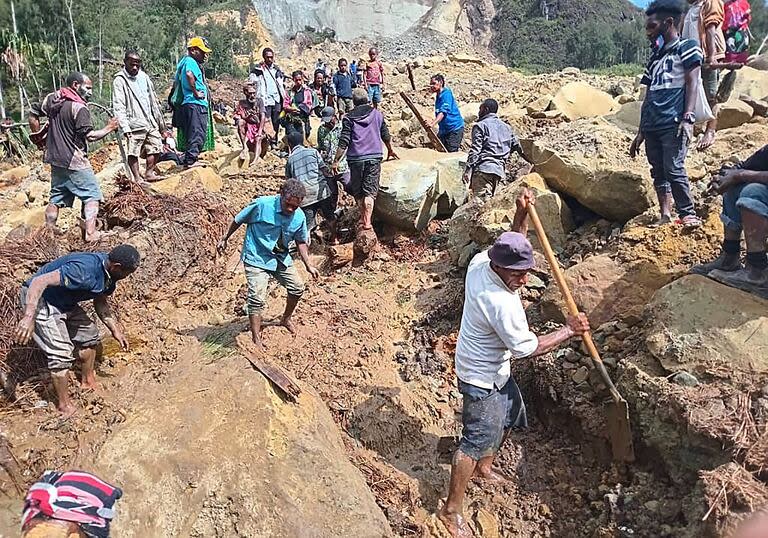 Esta foto tomada y recibida el 26 de mayo de 2024 de la Organización Internacional para las Migraciones muestra a personas excavando en el lugar de un corrimiento de tierras en la aldea de Yambali, en la región de Maip Mulitaka, en la provincia de Enga, en Papúa Nueva Guinea.