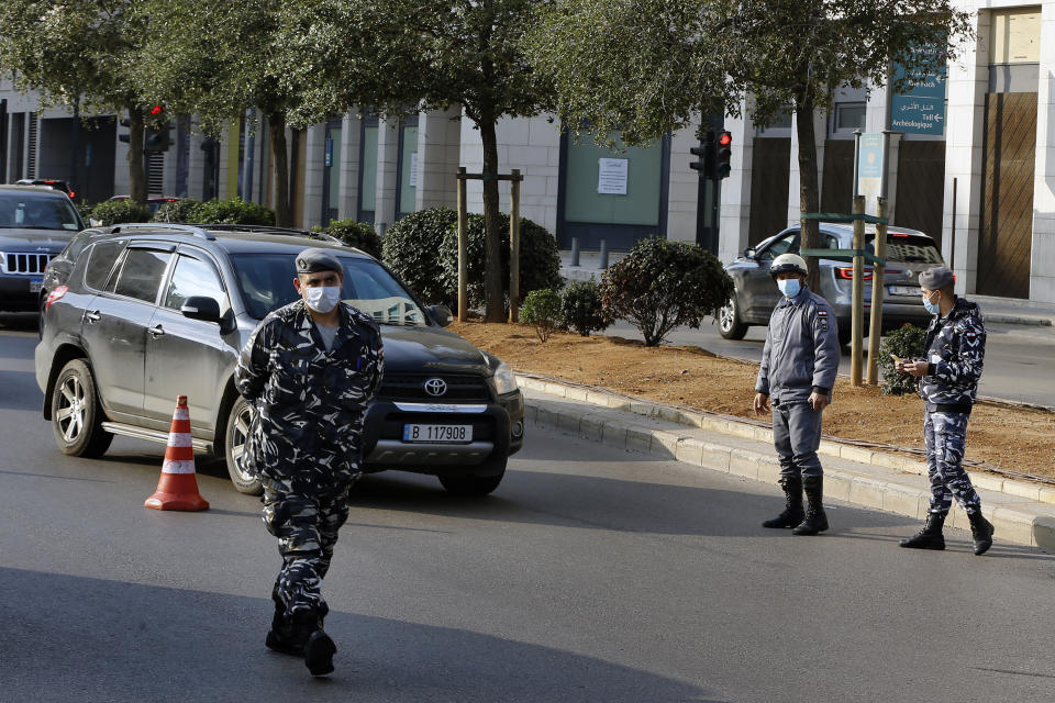 Police officers stand at a checkpoint to inspect cars that violate the odd and even license plate rule on alternating days as the country began a three-week lockdown to limit the spread of coronavirus amid a post-holiday surge in the past 10 days in Lebanon, Thursday, Jan. 7, 2021. (AP Photo/Bilal Hussein)
